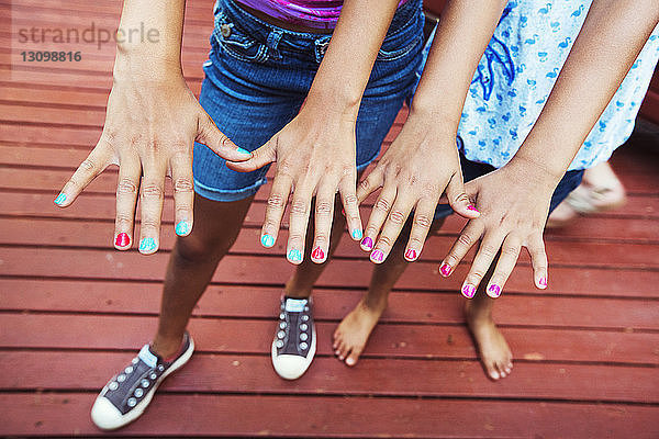 Unterer Teil von Mädchen  die Nagellack auf Fingernägeln zeigen  während sie im Hof stehen
