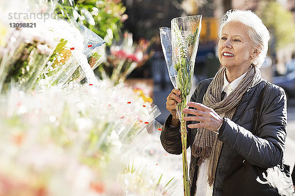 Ältere Frau kauft Blumen am Marktstand
