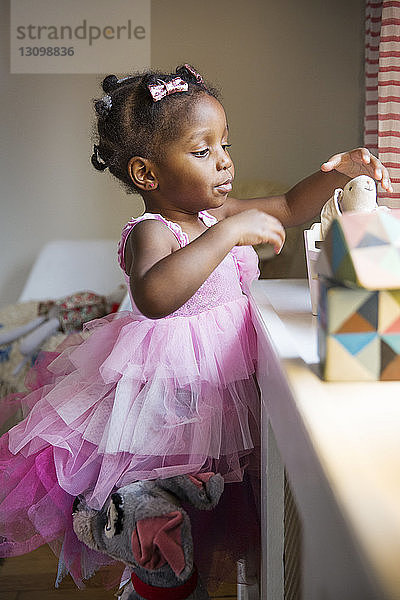 Süßes Mädchen in rosa Kleid nimmt zu Hause Spielzeug aus der Schachtel