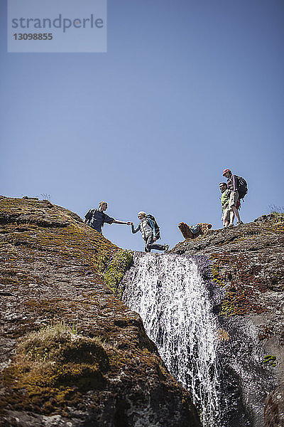 Tiefblick auf Freunde beim Wandern auf dem Berg bei klarem Himmel