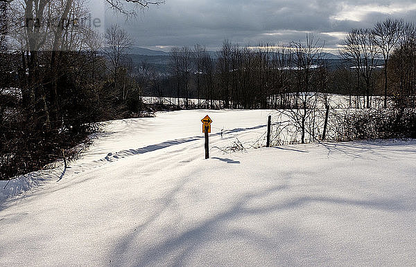 Pfeilsymbol auf schneebedeckter Landschaft vor bewölktem Himmel