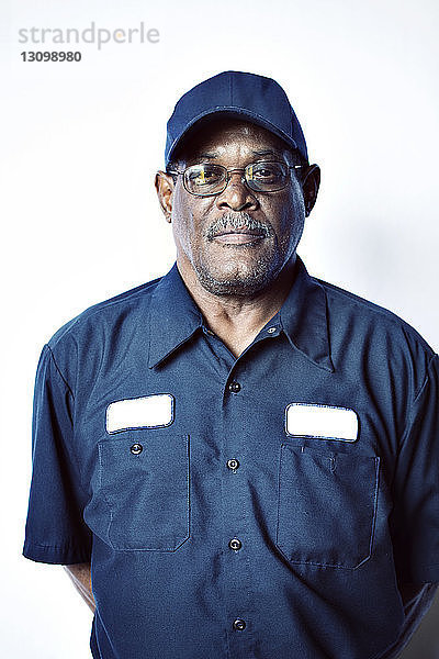 Porträt eines lächelnden älteren Arbeiters vor weißem Hintergrund stehend