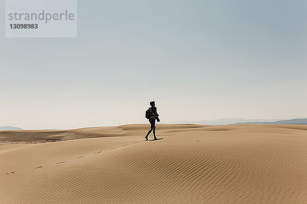 Wanderer in voller Länge mit Rucksack erkundet Wüste gegen den Himmel