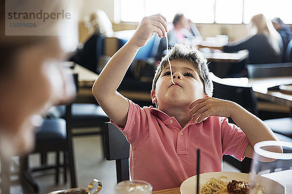 Süßer Junge isst Nudeln am Restauranttisch