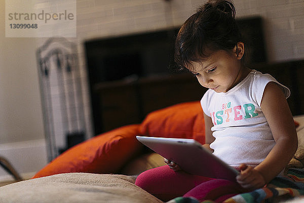 Mädchen benutzt Tablet-Computer zu Hause kniend