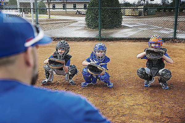 Rückansicht eines Trainers  der Baseball-Fänger auf dem Spielfeld trainiert