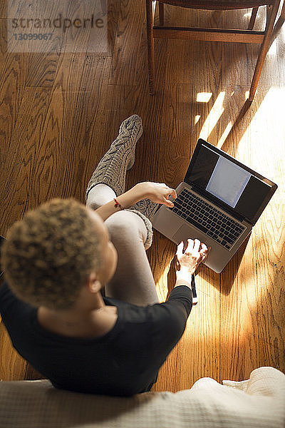 Draufsicht einer Frau  die einen Laptop auf dem Hartholzboden im Schlafzimmer benutzt