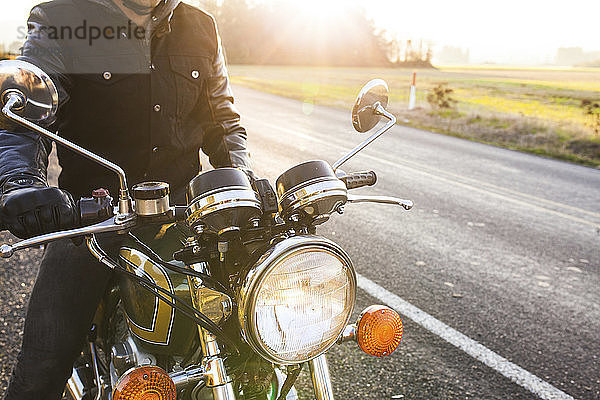 Mittelteil eines Motorradfahrers  der an einem sonnigen Tag auf einem Straßenmotorrad sitzt