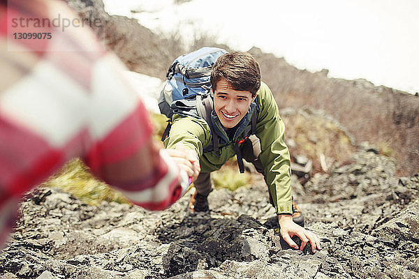 Ausgeschnittenes Bild einer Frau  die einem Freund beim Bergsteigen hilft