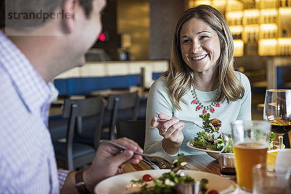 Glückliches Paar unterhält sich beim Salatessen im Restaurant