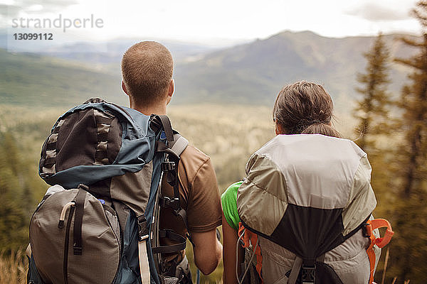 Rückansicht eines Paares mit Rucksäcken beim Blick auf Berge