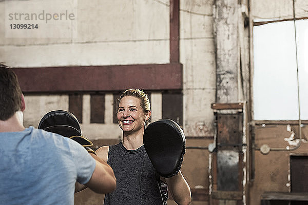 Glückliche Boxerin übt mit Freundin im Fitnessstudio