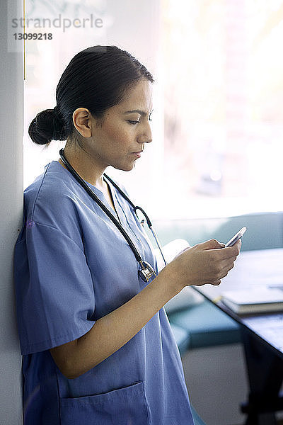 Ärztin benutzt Smartphone bei der Arbeit im Krankenhaus