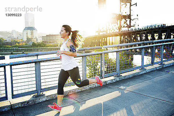 Frau in voller Länge auf der Brücke joggend