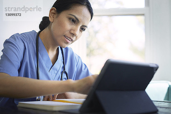 Ärztin  die während ihrer Arbeit in einer medizinischen Klinik einen Tablet-Computer benutzt