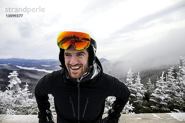Fröhlicher Mann mit Skikleidung gegen die Landschaft bei nebligem Wetter