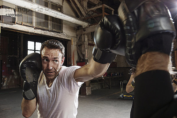 Entschlossener männlicher Boxer  der im Fitnessstudio trainiert