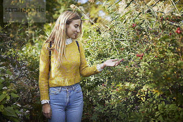 Lächelnde Frau betrachtet Pflanzen  während sie auf dem Feld steht
