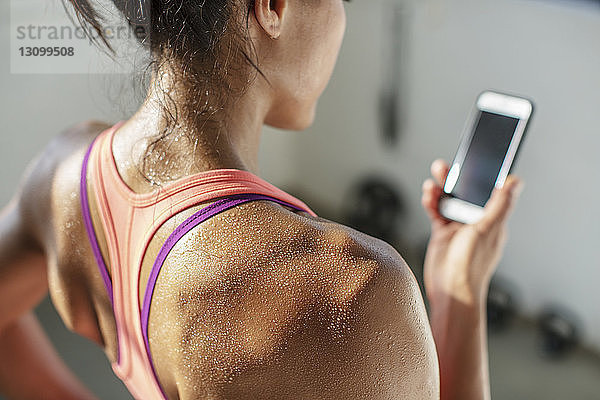 Nahaufnahme einer Sportlerin beim Gebrauch eines Mobiltelefons im Fitnessstudio