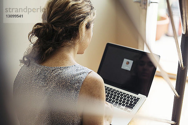 Rückansicht einer Frau  die auf einer Treppe sitzt und einen Laptop benutzt