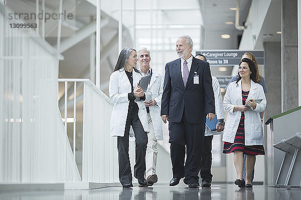 Leitender Arzt bespricht sich mit Kollegen beim Gang durch den Krankenhauskorridor