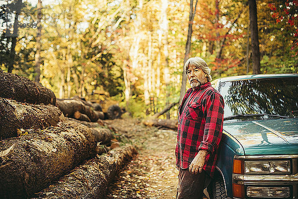 Seitenansicht Porträt eines Holzfällers  der im Wald am Auto steht