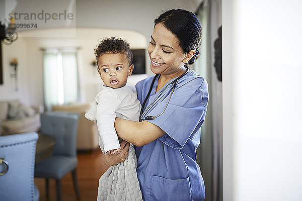 Lächelnder Kinderarzt trägt einen kleinen Jungen aus  während er zu Hause steht