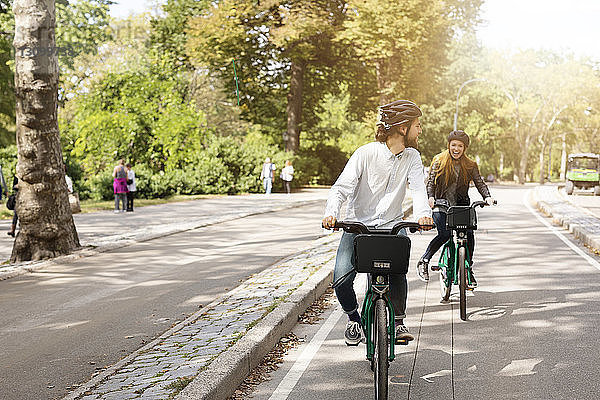 Glückliches Paar fährt Fahrrad auf Straße im Park