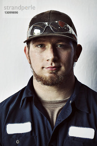 Porträt eines jungen Arbeiters mit Mütze vor weißem Hintergrund