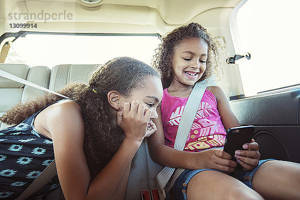 Mädchen schauen auf Smartphones  während sie im Auto unterwegs sind