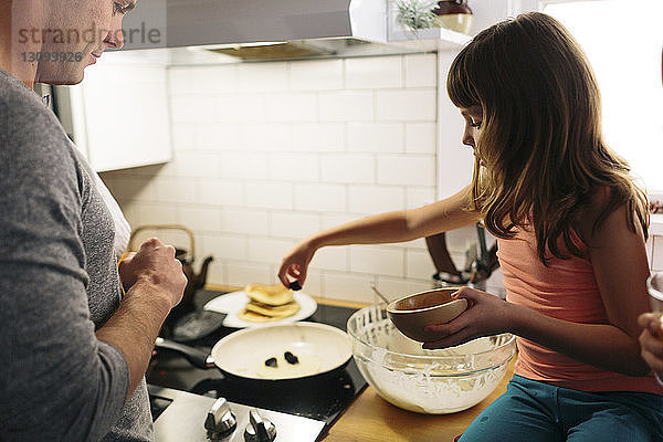 Vater und Tochter bereiten zu Hause in der Küche das Essen vor