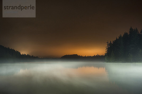 Lange Exposition des Nebels über dem See im Mt Hood National Forest gegen den Himmel bei Sonnenuntergang