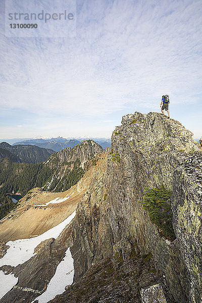 Niedrigwinkelansicht eines Wanderers mit Rucksack  der den Berg gegen den Himmel besteigt