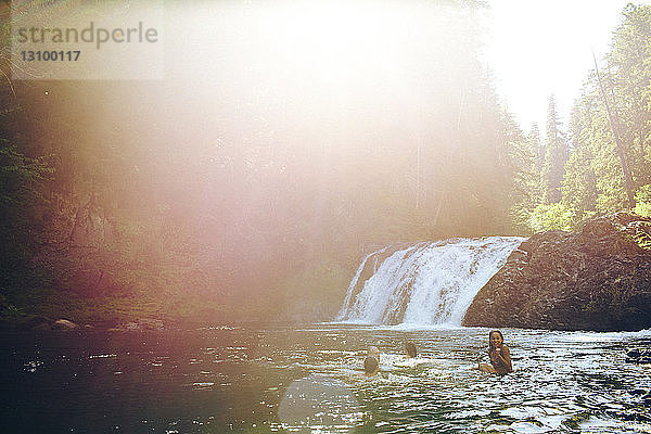 Freunde schwimmen bei Sonnenschein im Fluss im Wald