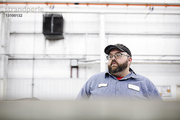 Arbeiter schaut weg  während er in einer Fabrik der Stahlindustrie steht