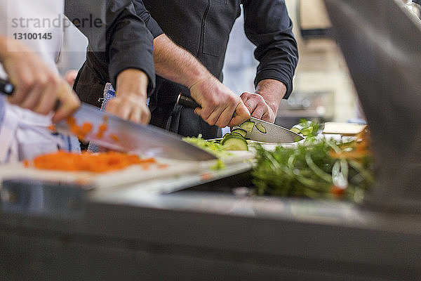 Mittelteil von Köchen  die in der Restaurantküche Gemüse zerkleinern