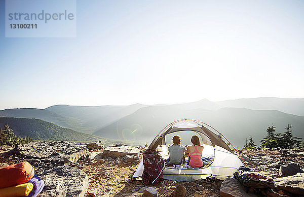 Rückansicht eines Paares  das sich im Zelt auf dem Berg entspannt