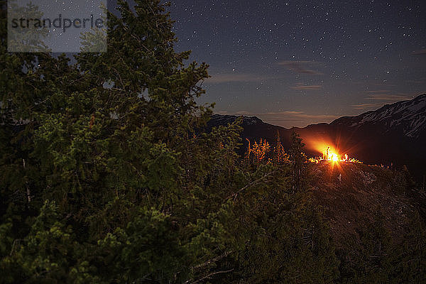 Ansicht eines Lagerfeuers  das nachts auf einem Feld gegen ein Sternenfeld glüht
