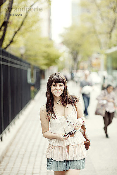 Porträt einer glücklichen Frau auf dem Bürgersteig stehend