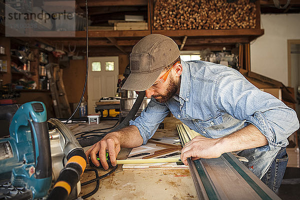 Seriöser Handwerker misst Holzkunst in der Werkstatt