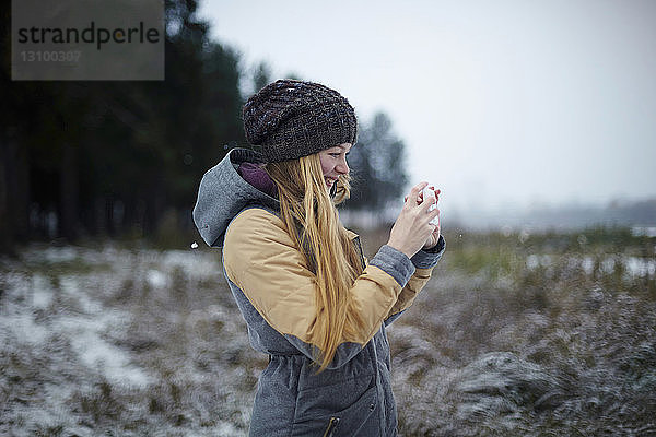 Frau fotografiert im Winter per Handy