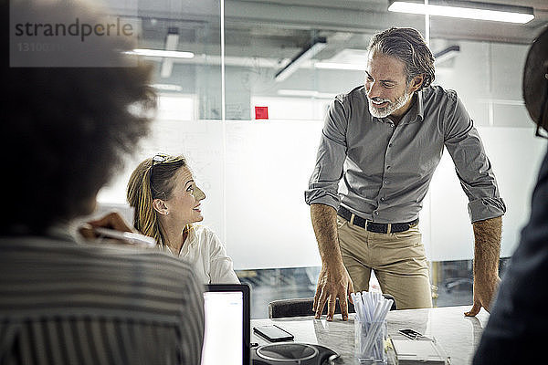 Männliche und weibliche Kollegen lächeln während der Besprechung im Büro