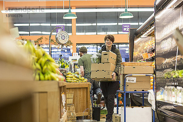 Arbeitnehmerin  die bei der Arbeit im Supermarkt Kartons trägt