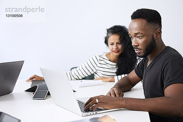Geschäftsleute  die mit Laptop-Computer am Konferenztisch im Büro arbeiten