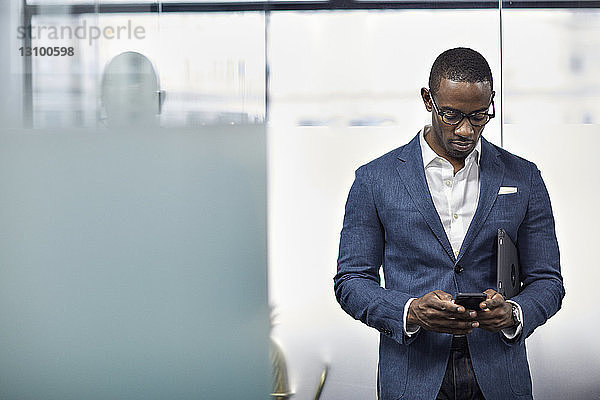 Geschäftsmann mit Smartphone im Stehen im Büro