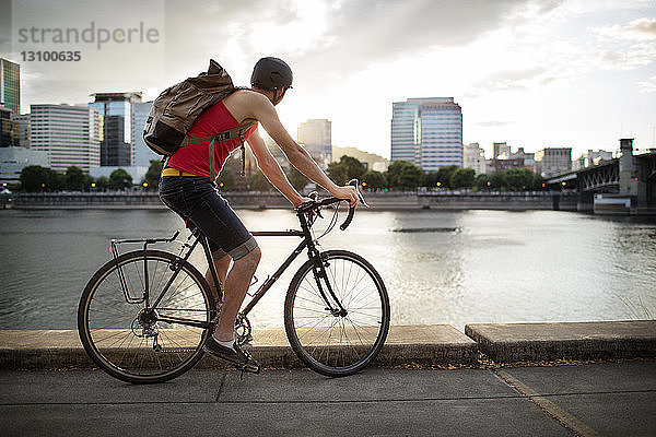Sportler mit Rucksack beim Fahrradfahren auf der Straße am See in der Stadt