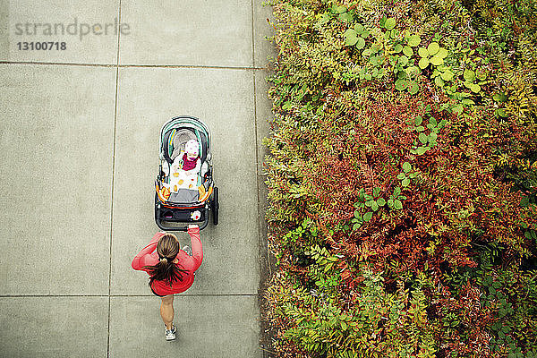 Draufsicht einer Frau  die rennt  während sie einen Kinderwagen im Park hält