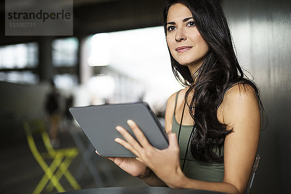 Nachdenkliche junge Frau hält Tablet-Computer im Freien