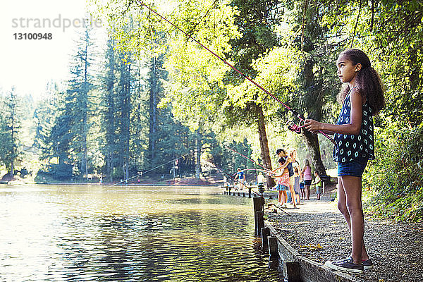 Seitenansicht eines Mädchens beim Angeln im See an einem sonnigen Tag