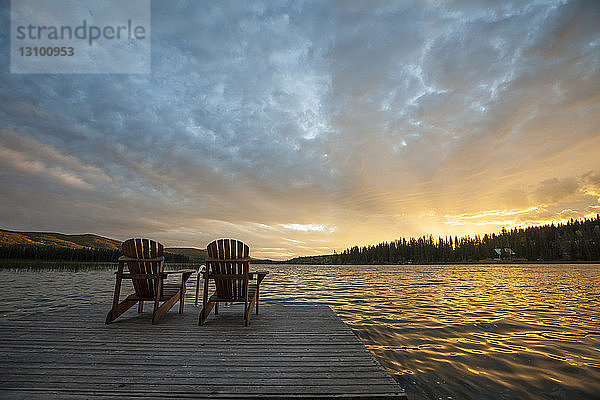 Stühle auf der Mole am See Lac Le Jeune im Paul Lake Provincial Park gegen den Himmel bei Sonnenuntergang